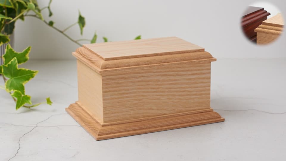 A light-coloured, traditional casket. A rectangular cuboid shape with an overhanging top and base. Both top and base have bead routing profiles, producing a simple and elegant appearance