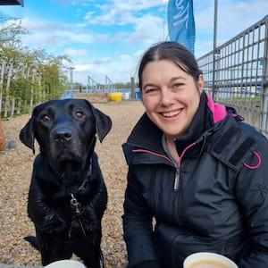 Profile picture of Fern, a care coordinator, on a beach with her black Labrador
