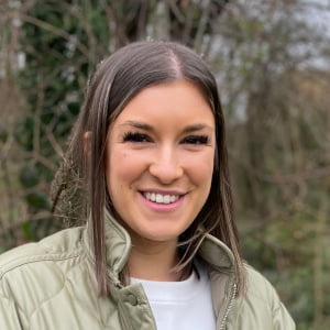 Profile picture of Lauren, a care coordinator, standing in front of a small copse